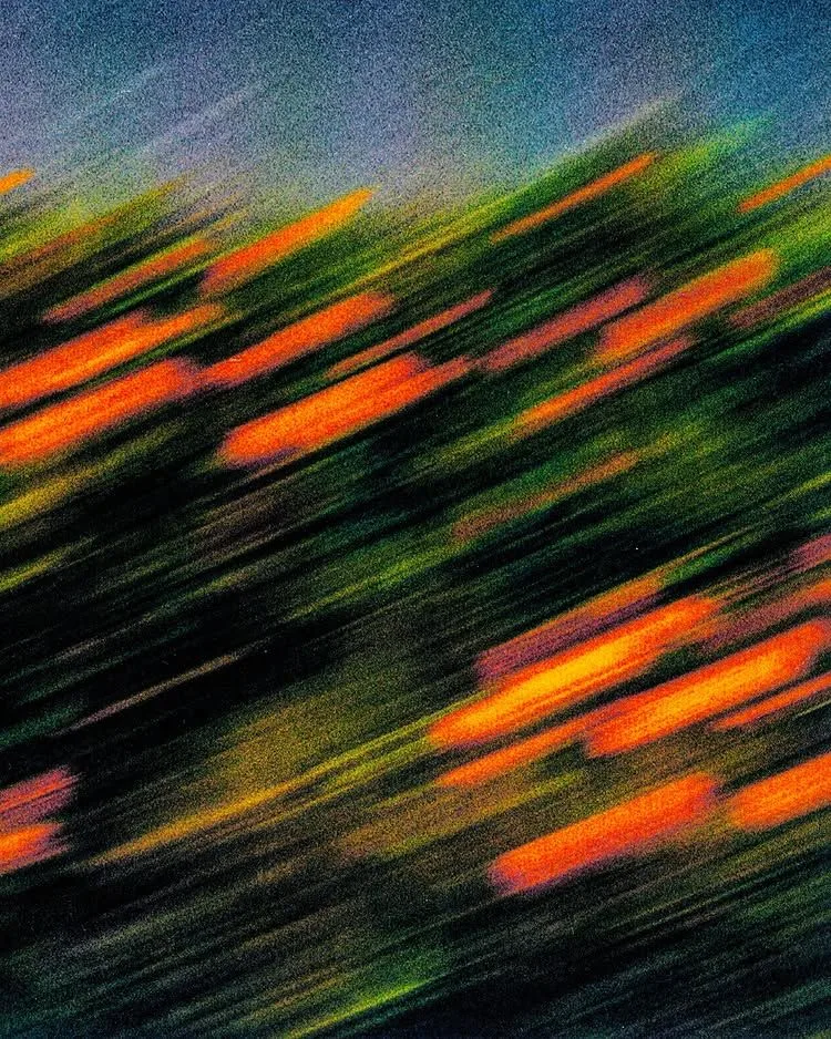 Orange flowers blurred into streaks by fast movement, against dark green foliage.