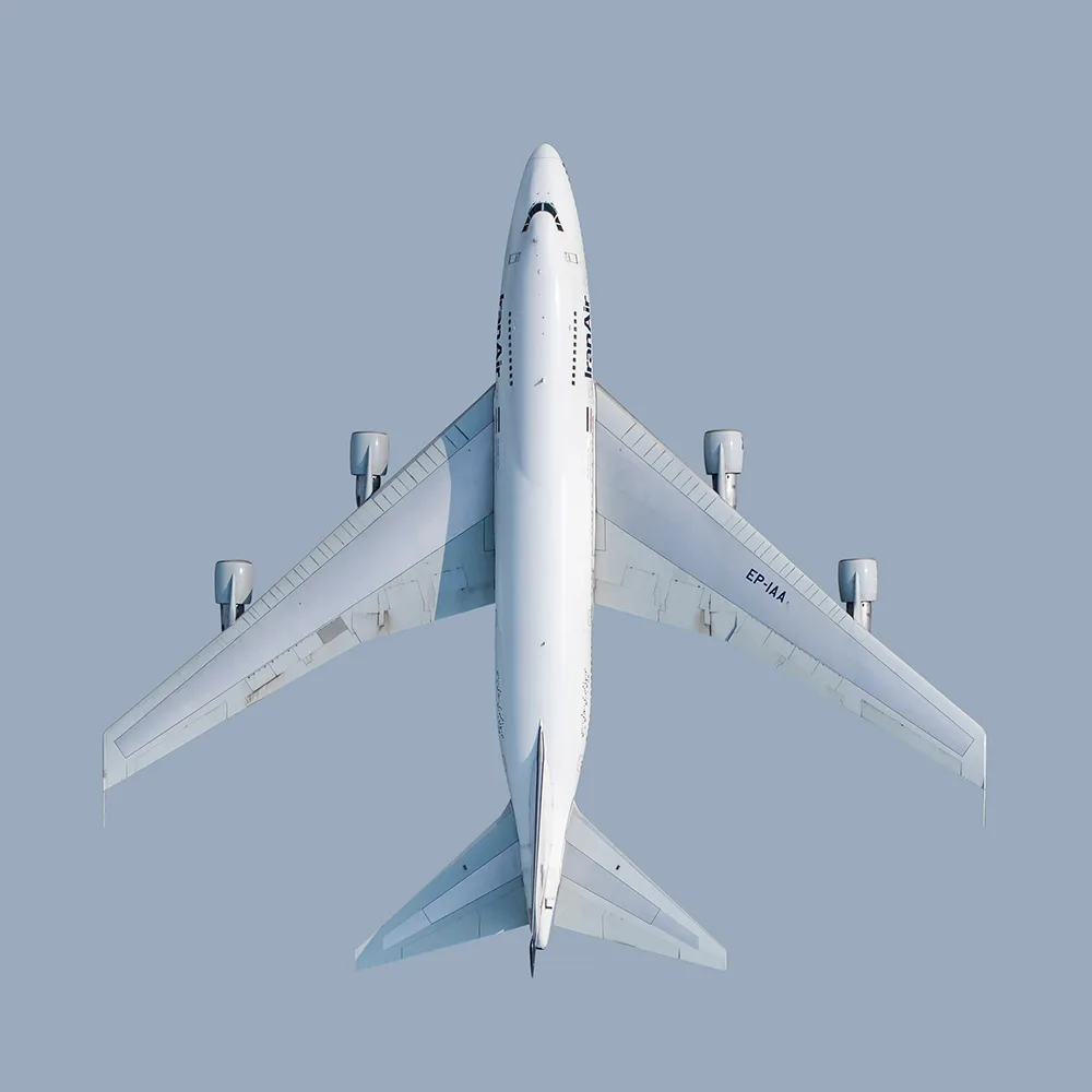 A white jet airliner seen directly from above against a flat blue-grey background.
